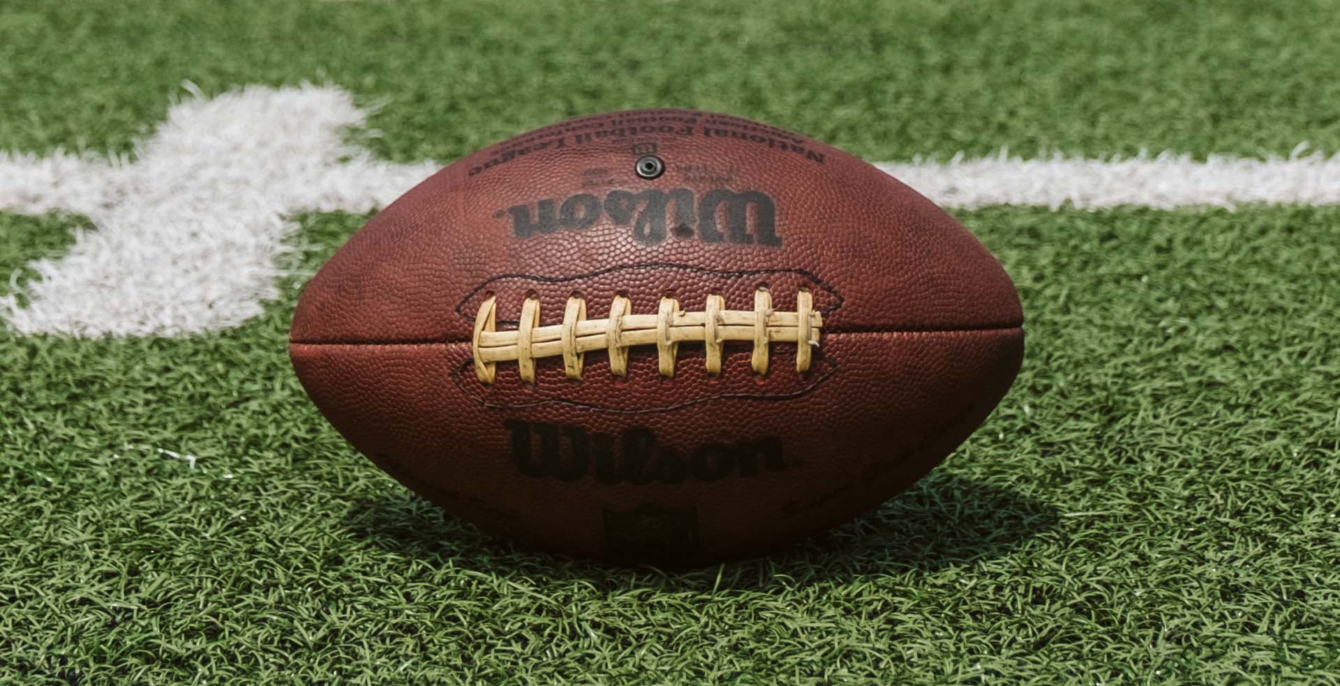 A Wilson football on a green turf field.